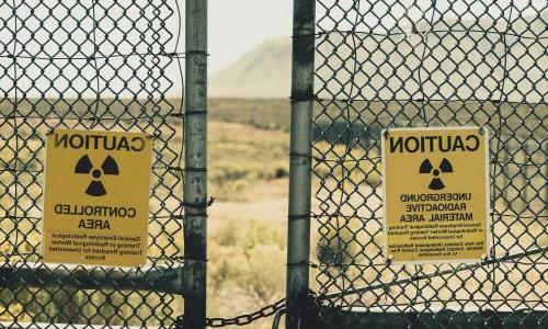 有辐射警告标志的栅栏和沙漠景观的背景